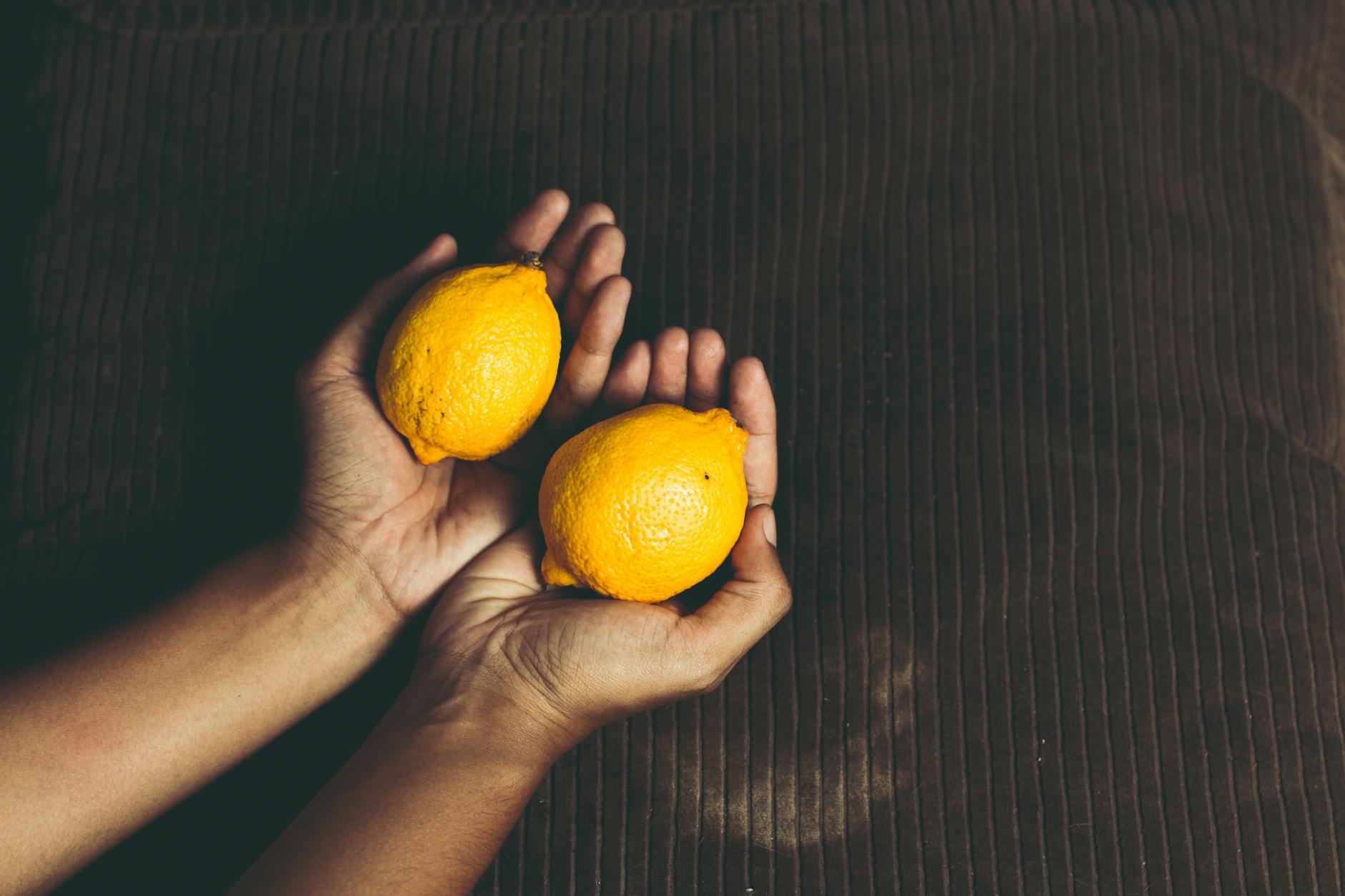 Close-up of a hand holding an orange vibrator against a purple backdrop, showcasing modern sensuality