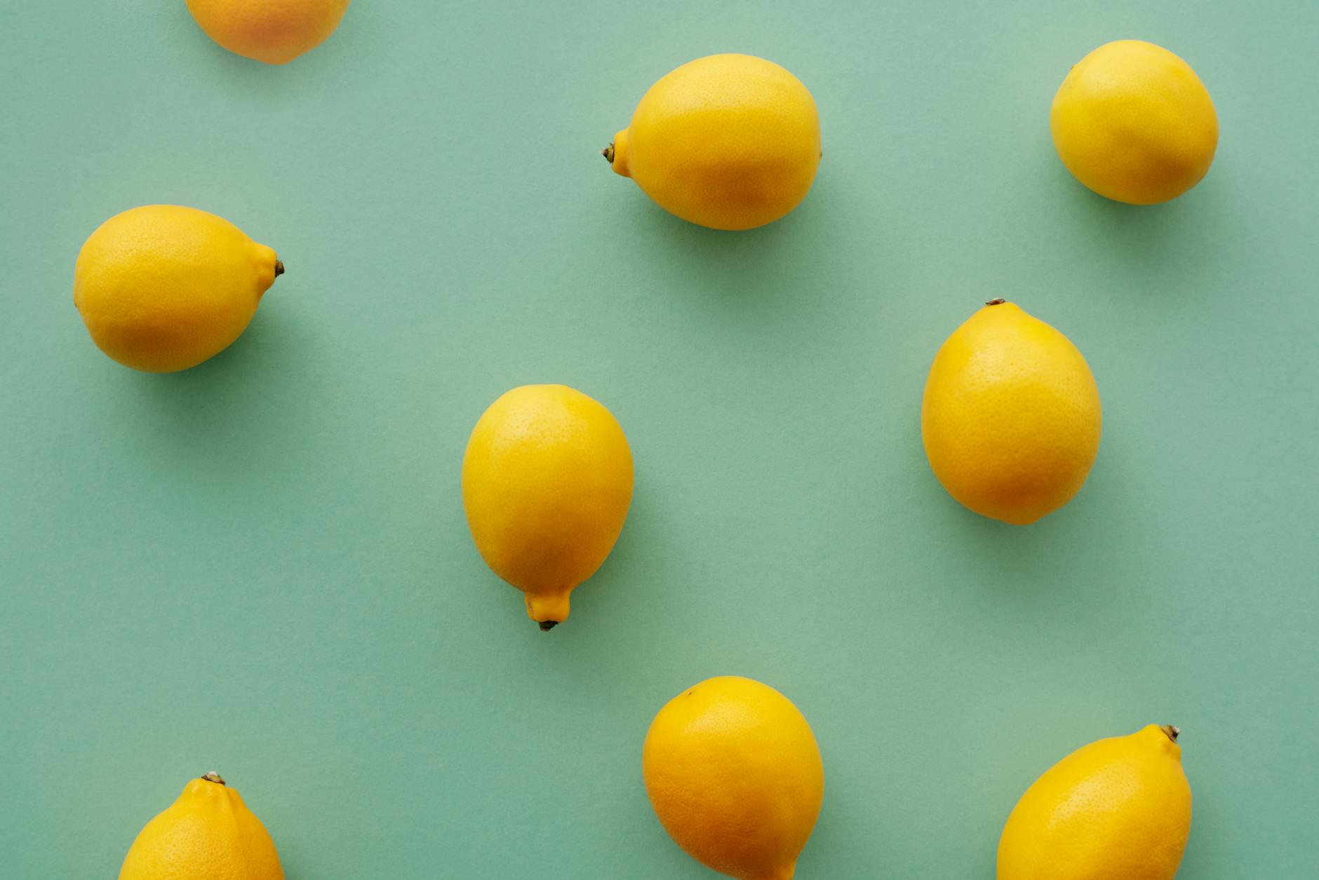 Bright yellow lemons arranged on a pastel green background, evoking freshness and renewal