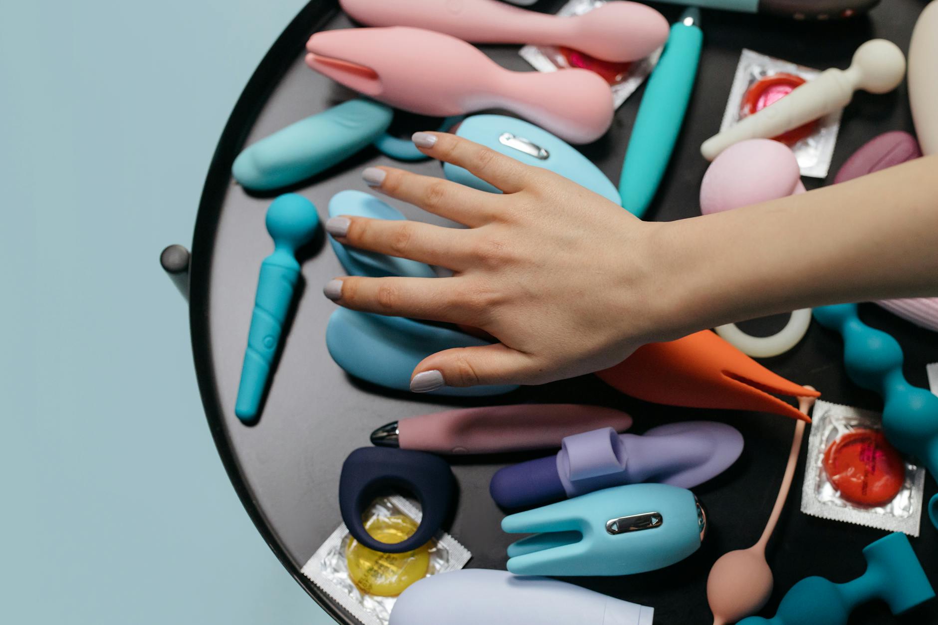 Hands holding a sleek blue vibrator against a purple background, representing intimate self-exploration.