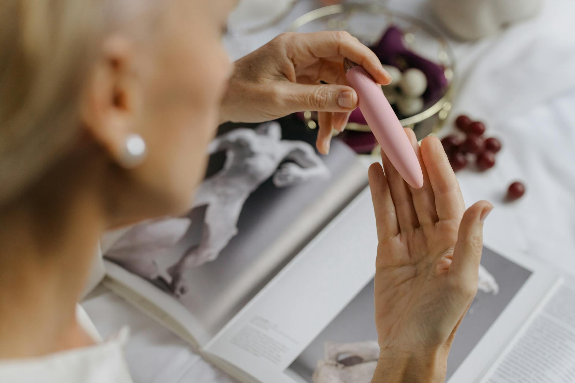 Close-up of a woman holding a pink vibrator surrounded by intimate personal items, symbolizing reconnection with pleasure