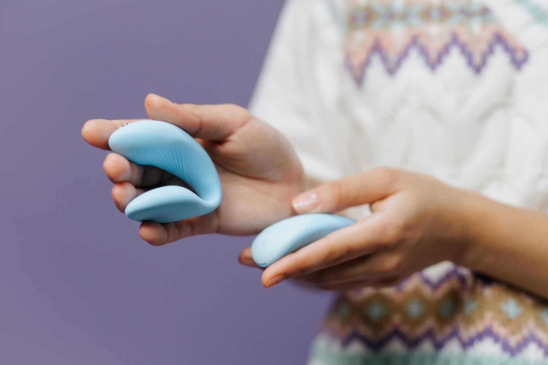 Mão segurando um vibrador de limão azul escuro contra fundo roxo