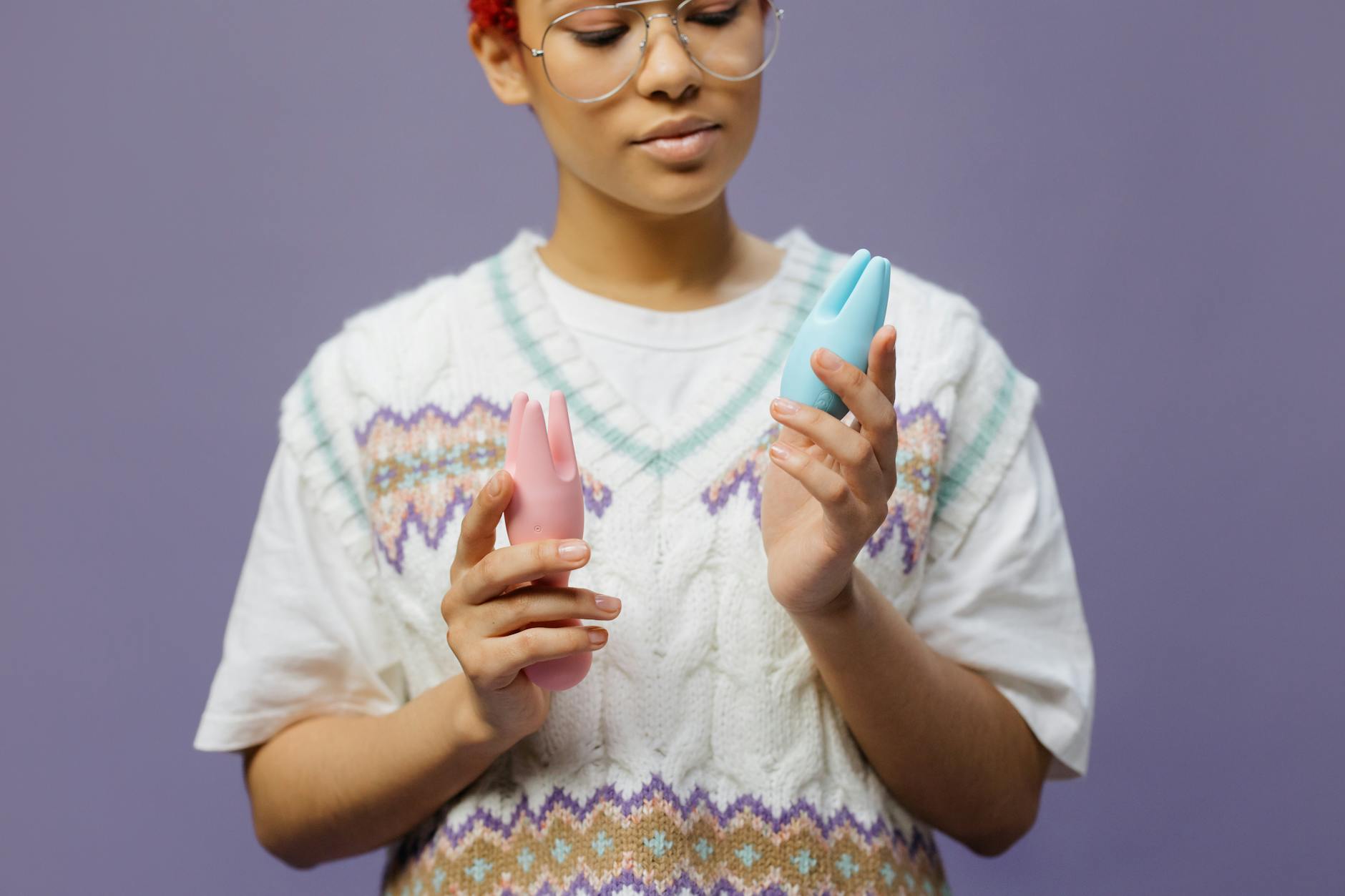 Woman holding colorful clitoral vibrators, exploring solo pleasure for the first time