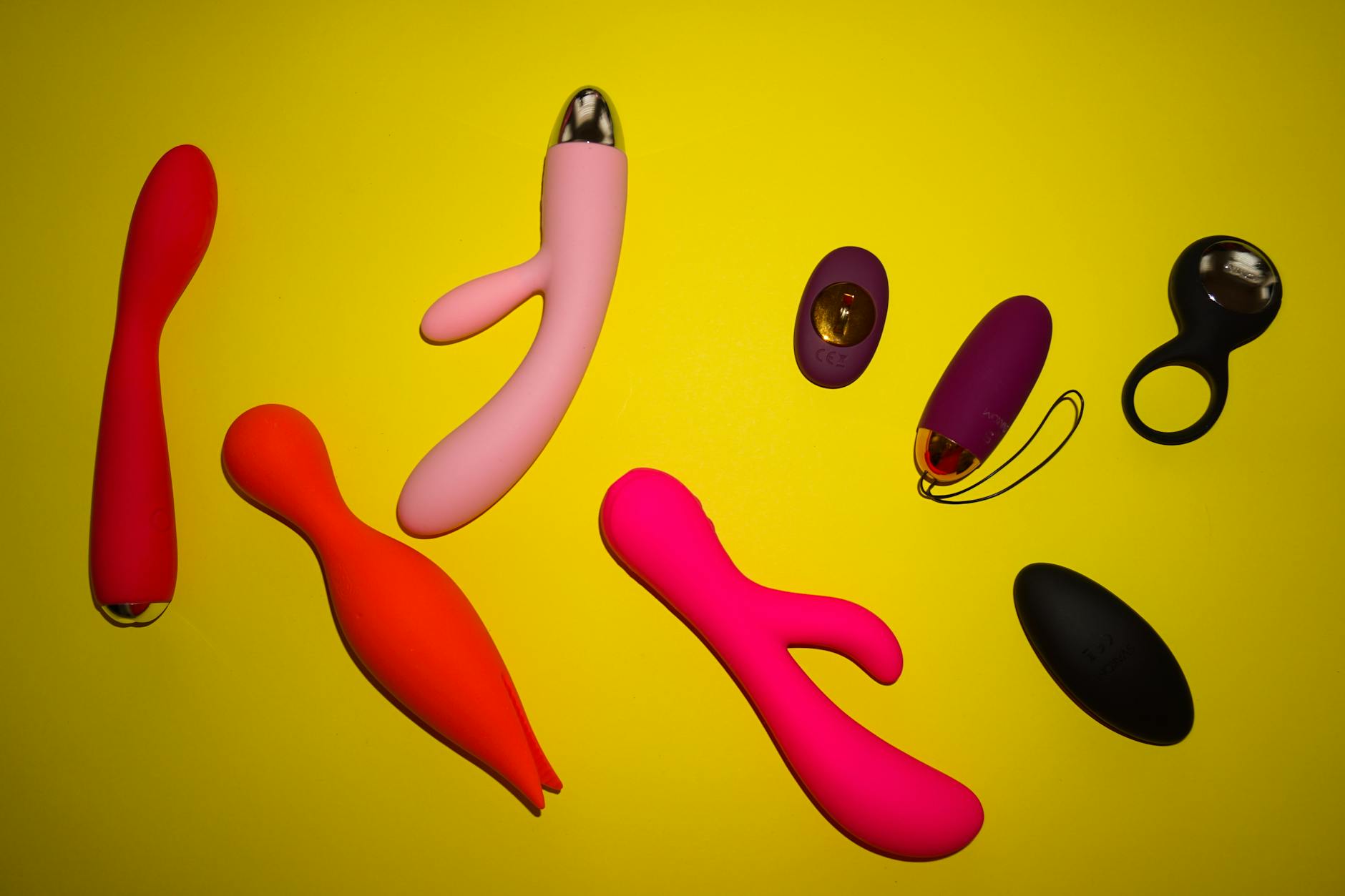 Vibrant collection of colorful vibrators and lemon clitoral vibrators on bright yellow surface